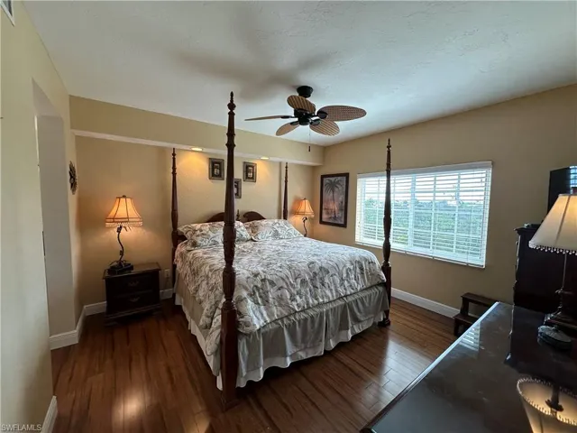Spacious room featuring wood-finish flooring, a ceiling fan, and a large window with horizontal blinds