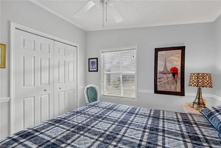 White bi-fold closet doors, ceiling fan, crown molding, and a window with blinds