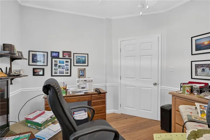 Wood-finish flooring, white paneled door, crown molding, and chair rail molding