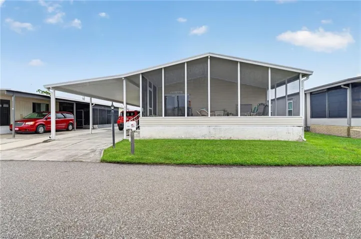 Screened front porch, covered carport, concrete driveway, and a maintained lawn
