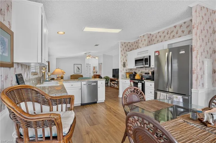 Kitchen featuring wood-finish flooring, white cabinetry, a stainless steel dishwasher, and stainless steel refrigerator