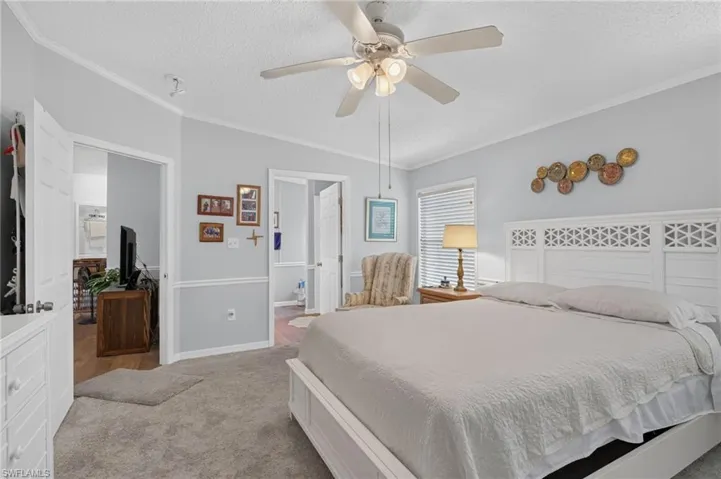 Spacious room with carpeted flooring, a ceiling fan with integrated lighting, window with blinds, and white crown molding