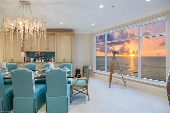 Tiled dining area featuring ornamental molding, a water view, and a notable chandelier