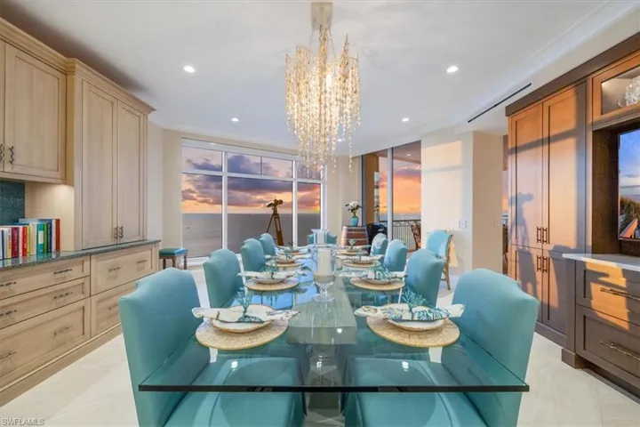 Tiled dining area featuring crown molding and a chandelier