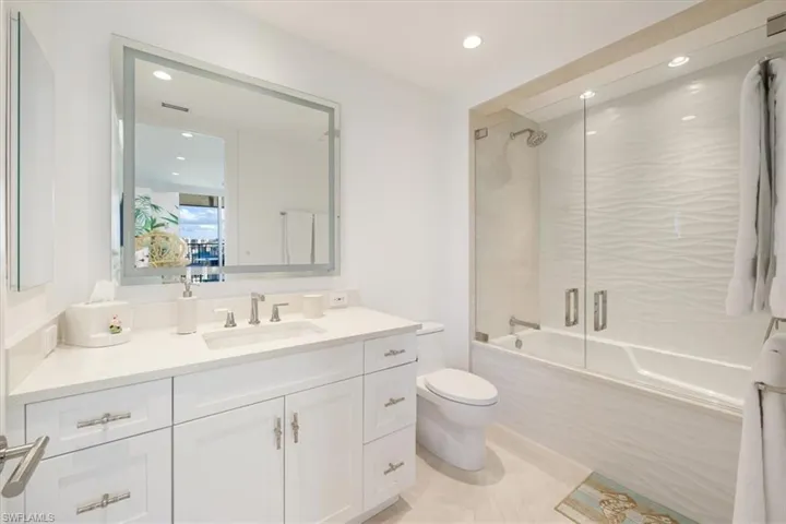 Full bathroom featuring tile patterned flooring, toilet, vanity, and combined bath / shower with glass door