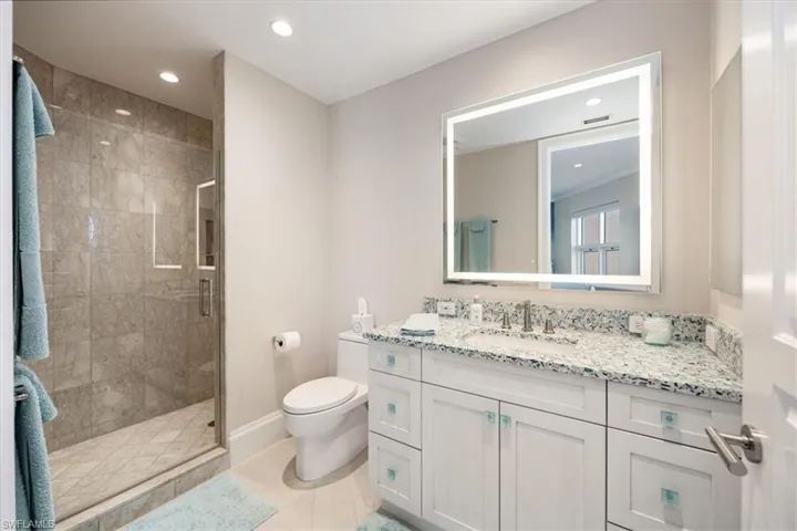 Bathroom featuring tile patterned flooring, vanity, toilet, and a shower with shower door