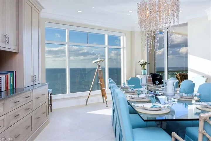 Dining space with a notable chandelier, a water view, and crown molding