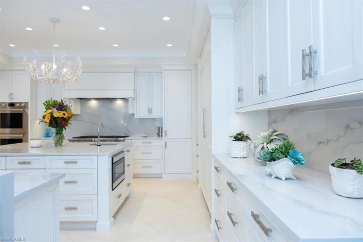 Kitchen with white cabinetry, an inviting chandelier, tasteful backsplash, decorative light fixtures, and appliances with stainless steel finishes