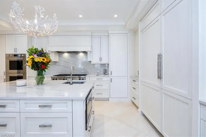 Kitchen with decorative backsplash, white cabinetry, and appliances with stainless steel finishes