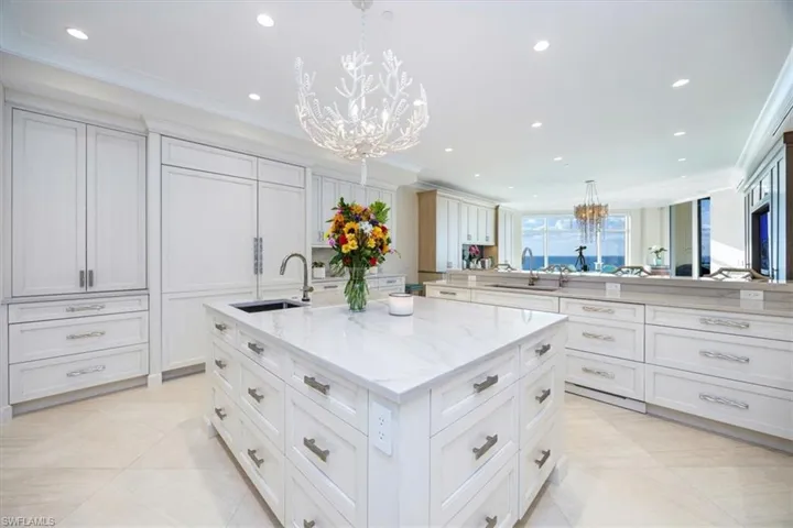 Kitchen with decorative light fixtures, a spacious island, ornamental molding, and sink