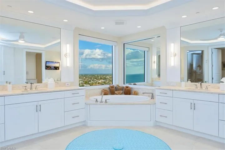 Bathroom featuring tile patterned flooring, vanity, a tray ceiling, and ornamental molding