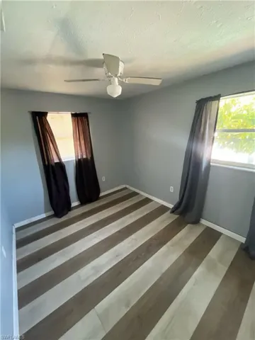 Unfurnished room with wood finished floors, a ceiling fan, and a textured ceiling