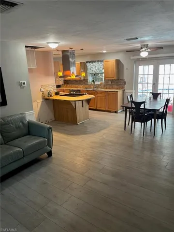 Kitchen featuring island exhaust hood, ceiling fan, a kitchen bar, visible vents, and a peninsula