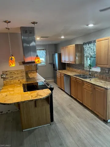 Kitchen featuring appliances with stainless steel finishes, light wood-style floors, backsplash, and a sink
