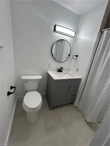 Bathroom with tile patterned flooring, vanity, toilet, and curtained shower