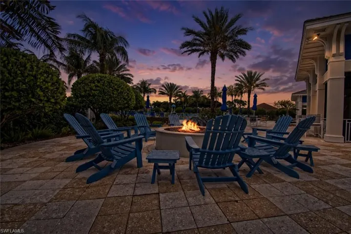 Watermark Community patio with a circular fire pit and surrounding blue Adirondack chairs