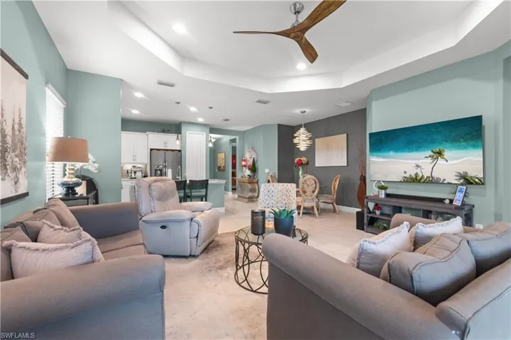 Open-concept living area featuring a tray ceiling with a contemporary ceiling fan, recessed lighting, and tile flooring