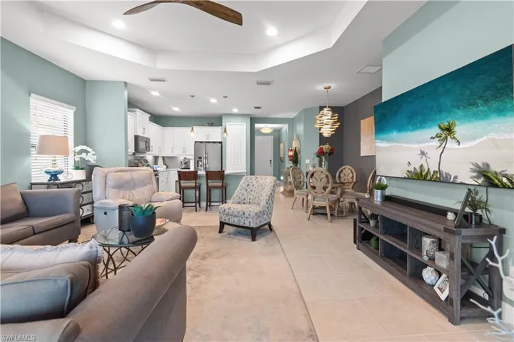 Open-concept living space featuring a tray ceiling, recessed lighting, and a wood-finish ceiling fan