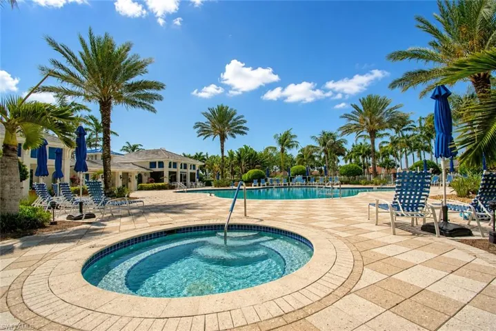 Outdoor spa with an adjacent swimming pool, surrounded by a paver patio and mature palm trees