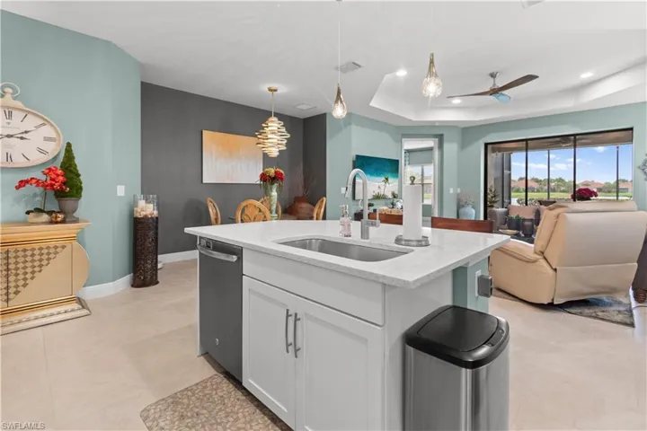 Kitchen island with white cabinetry, integrated sink, and stainless steel dishwasher