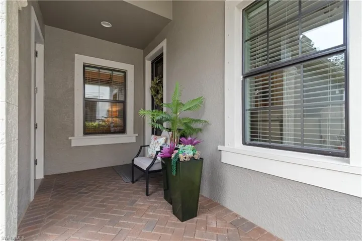 Covered entry porch featuring brick paver flooring and stucco exterior walls