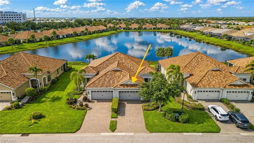 Residential property featuring a terracotta-tiled roof, stucco exterior, and a paver driveway
