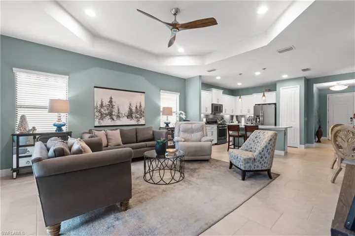 Open-concept living space featuring a tray ceiling with recessed lighting and a ceiling fan