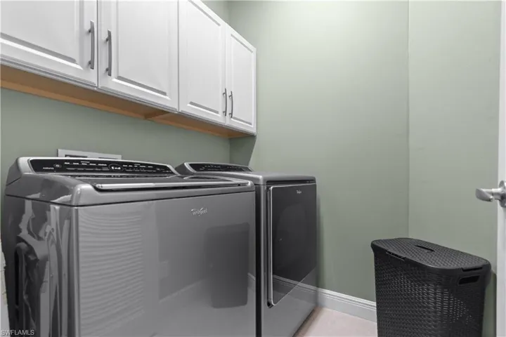 Laundry area featuring ample white cabinetry with brushed nickel hardware,