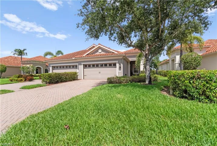 Mediterranean-style residence featuring a tile roof, light-toned exterior, and an attached two-car garage