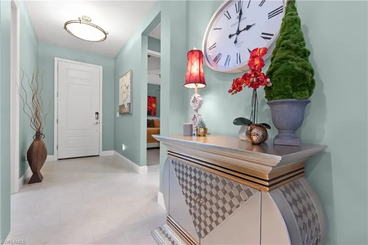 Entryway featuring light-colored tile flooring, a paneled white entry door, and hallway to the guest quarters
