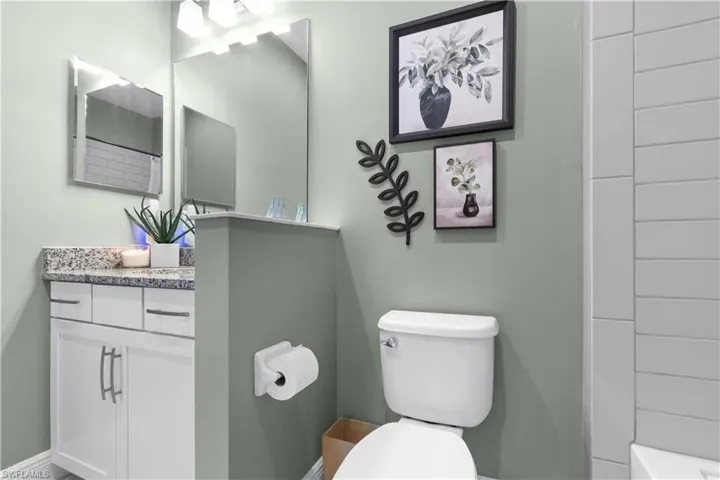 Bathroom featuring a vanity with a light-toned countertop, white cabinetry with brushed nickel hardware, and a framed mirror