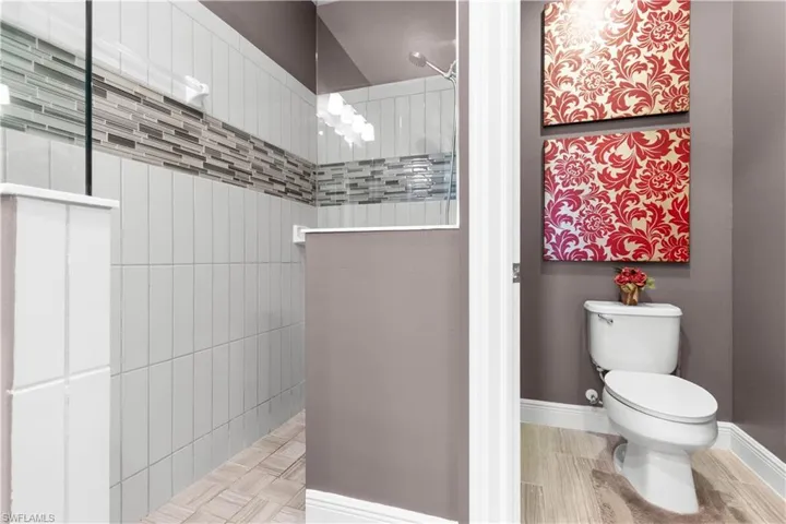 Shower enclosure with light-toned vertical tile and a decorative mosaic tile band