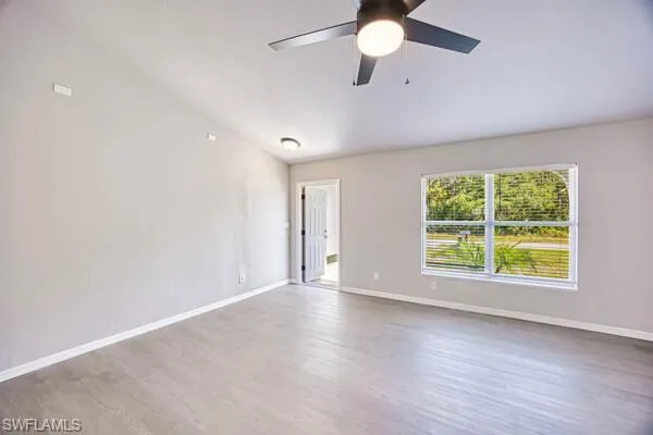 Unfurnished room featuring a ceiling fan, wood finished floors, and baseboards