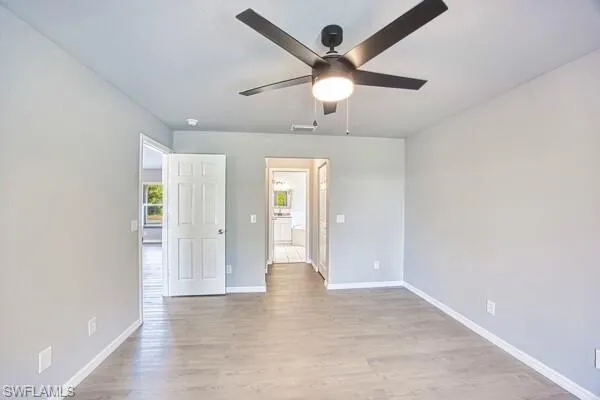 Primary bedroom featuring ceiling fan, light wood-style floors, and baseboards
