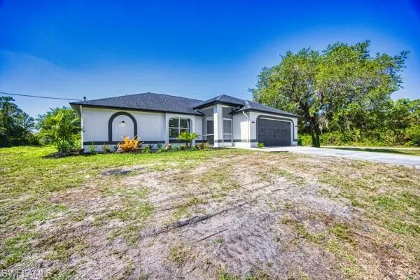 View of front of property featuring concrete driveway, a garage, and stucco siding