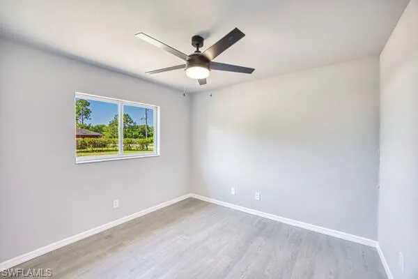 Guest bedroom with ceiling fan, wood finished floors, and baseboards