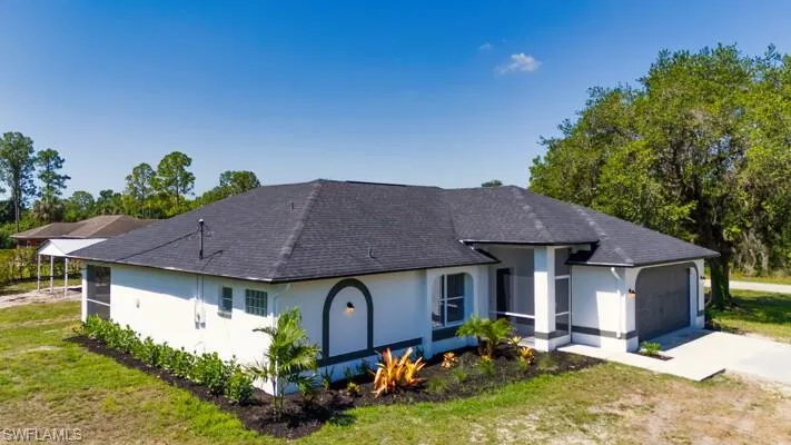Single story home with stucco siding, concrete driveway, an attached garage, a shingled roof, and a front yard