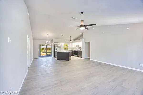 Unfurnished living room featuring a ceiling fan, baseboards, light wood-type flooring, and high vaulted ceiling
