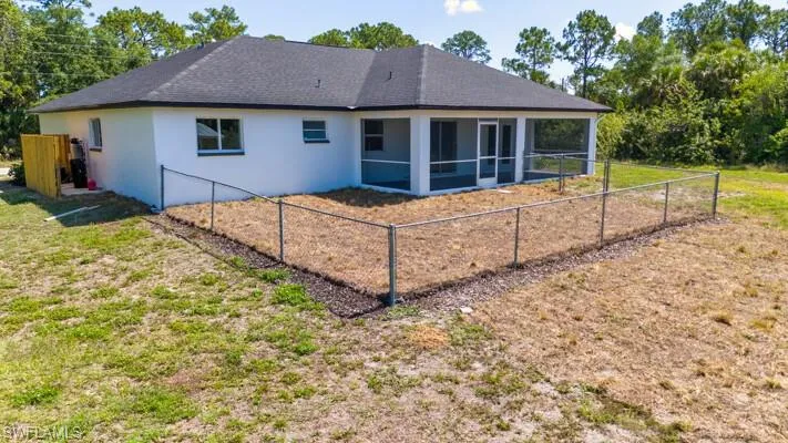 Rear view of house featuring a sunroom, stucco siding, and a fenced backyard