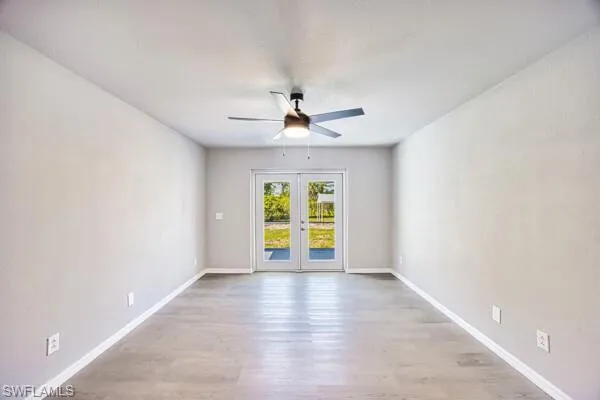 Primary bedroom featuring a ceiling fan, french doors, wood finished floors, and baseboards
