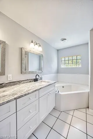 Primary Full bath featuring tile patterned floors, a garden tub, and vanity