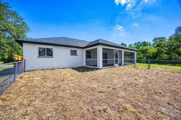 Rear view of property featuring a sunroom, stucco siding, and a fenced backyard