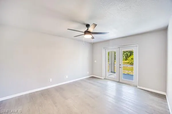 Primary bedroom with ceiling fan, wood finished floors, baseboards, and a textured ceiling