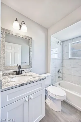 Full guest bathroom with wood finished floors, toilet, vanity, and shower / bath combination