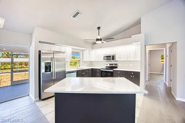 Kitchen with stainless steel appliances, lofted ceiling, light countertops, ceiling fan, and white cabinets