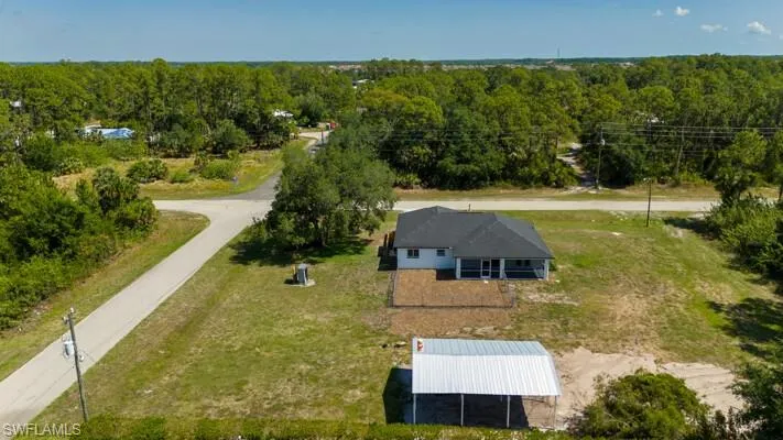 Aerial view of property and surrounding area with a forest