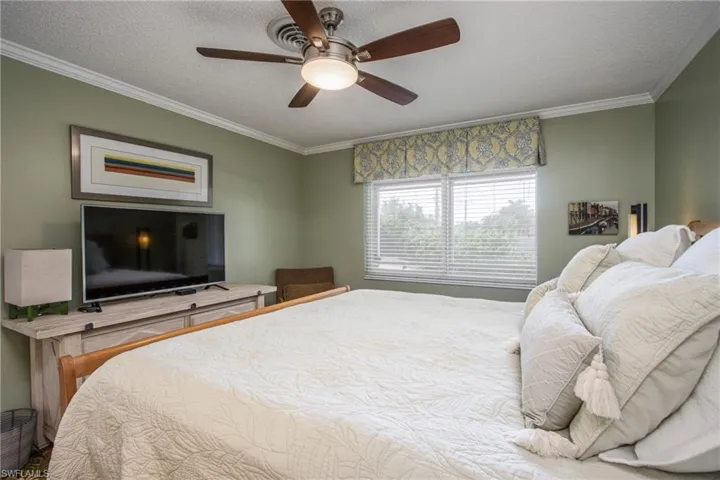 Bedroom featuring ceiling fan, ornamental molding, and a textured ceiling