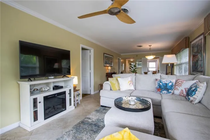 Tiled living room featuring ceiling fan and crown molding