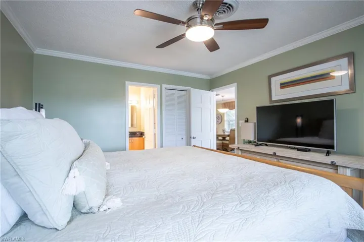 Bedroom with connected bathroom, a closet, ornamental molding, a textured ceiling, and ceiling fan