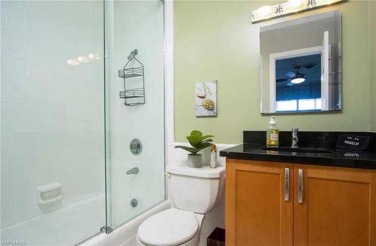 Full bathroom with vanity, shower / bath combination with glass door, toilet, and ceiling fan